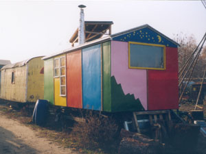 Einer der kunterbunten Wohnwagen des Wagendorfs, der einem kleinen Häuschen ähnelt.